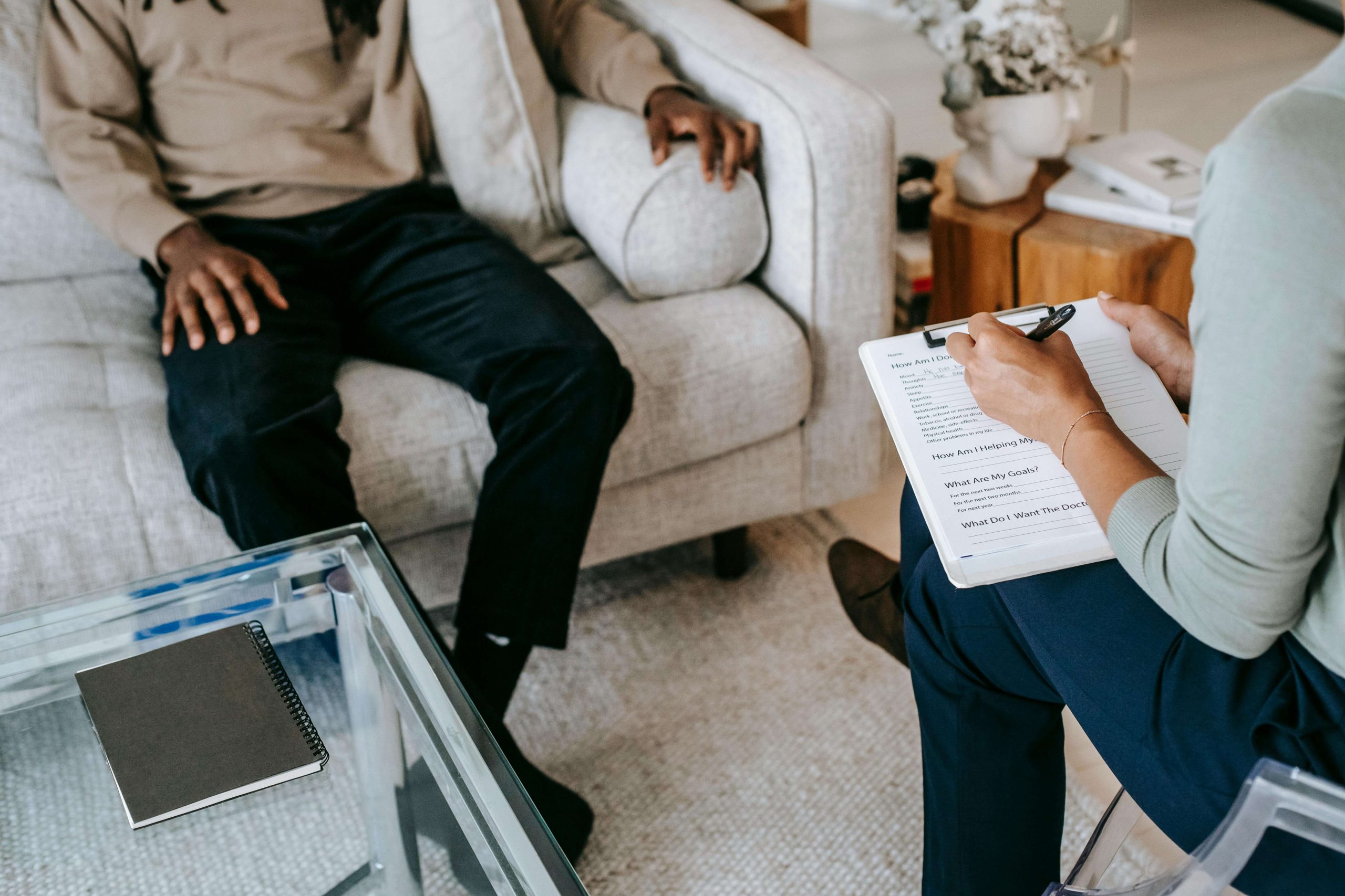 Close-up of a psychiatrist writing on a clipboard while speaking with a client during a psychiatry session in Tempe, AZ, focused on medication management.