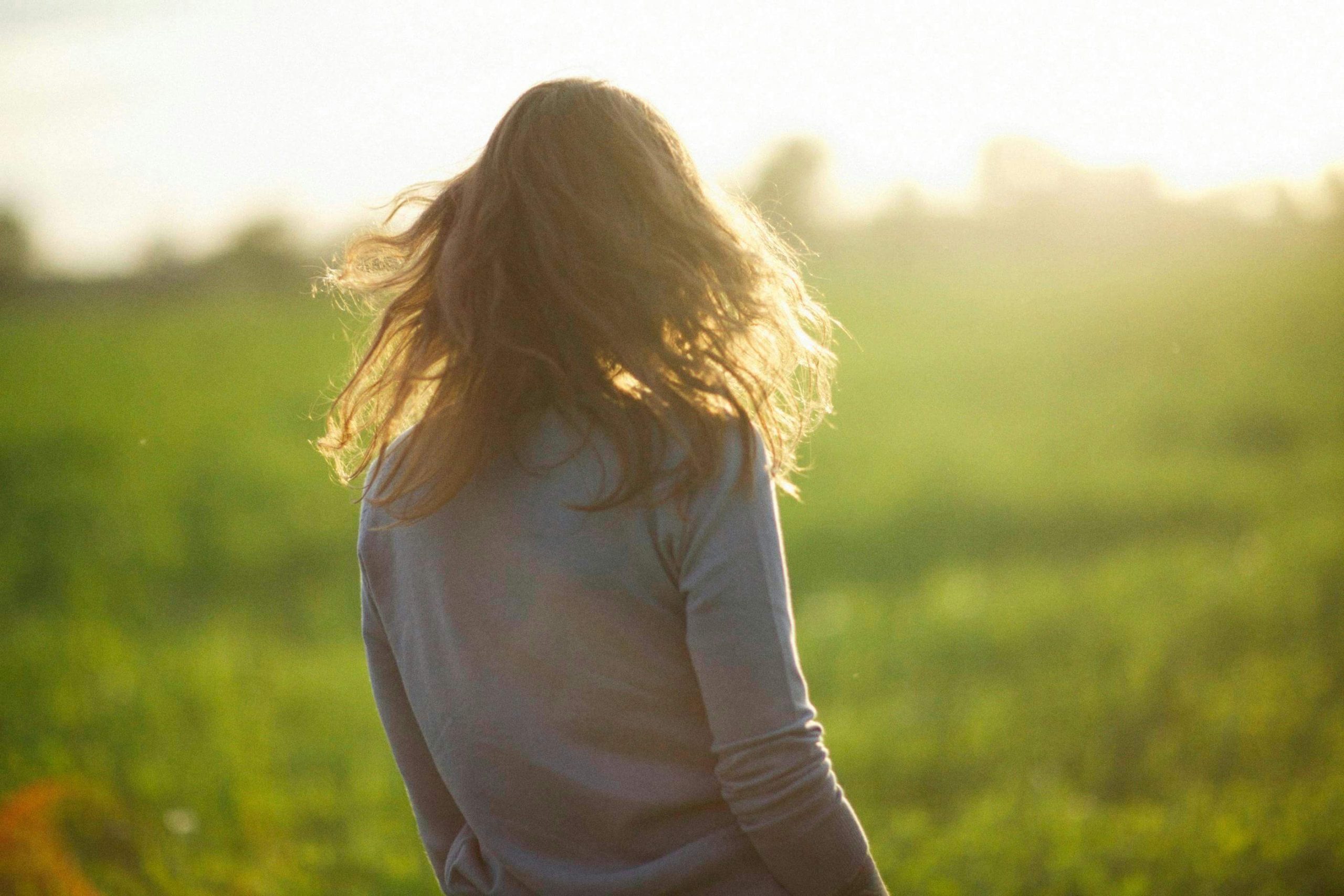 Woman standing in a sunlit field, reflecting on recovery and mental clarity with guidance from a psychiatrist in Tempe, AZ.