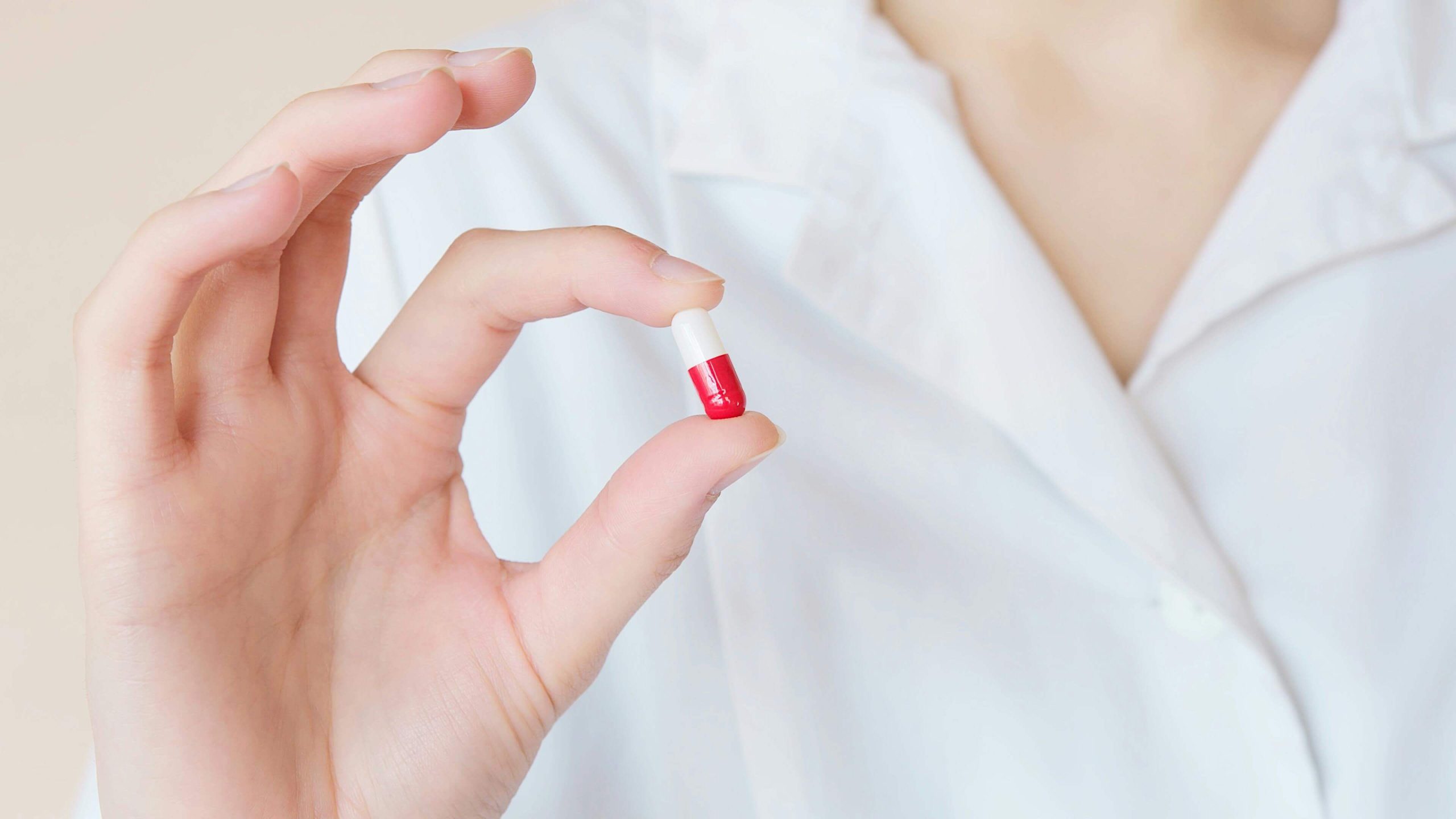 Close-up of a healthcare provider holding a red and white capsule, representing psychiatric care in Tempe for anxiety and depression.