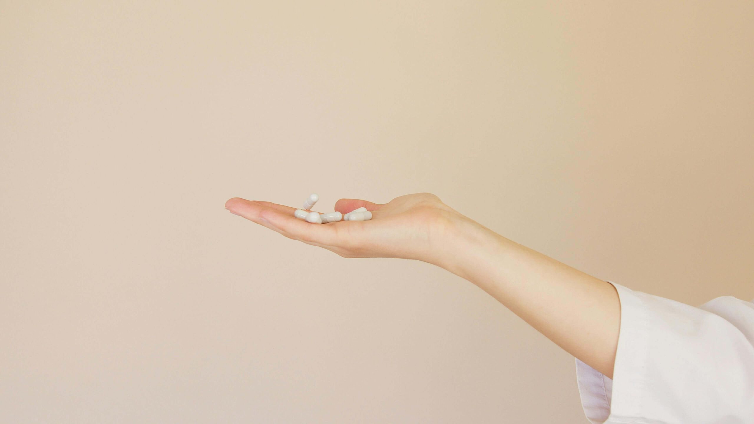 An outstretched hand holding several white capsules, representing medication prescribed through psychiatry in Tempe, AZ.
