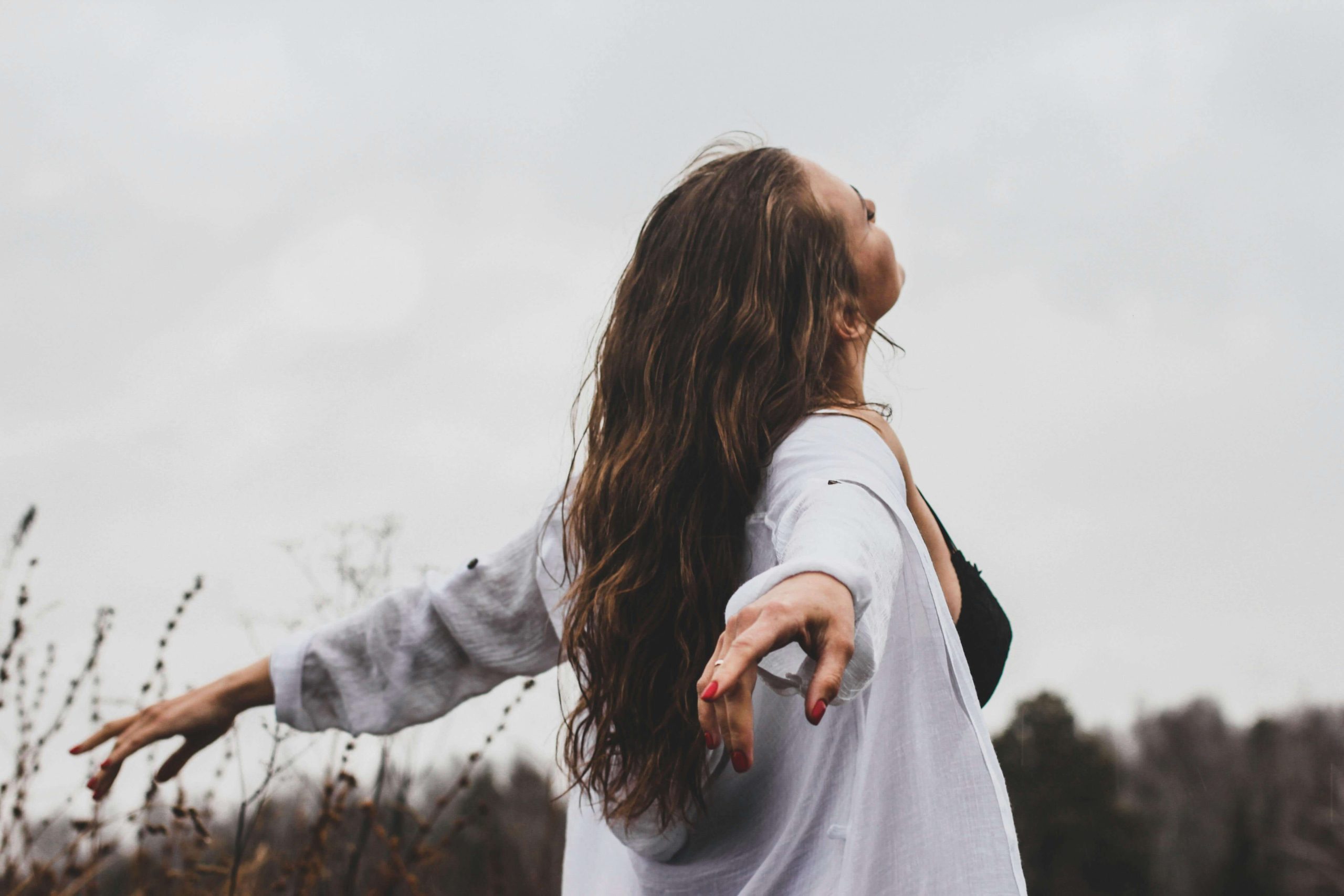 Person standing in a field with arms outstretched, embracing calm and renewal, representing the sense of balance and energy restoration that IV hydration therapy in Tempe, AZ can support for mental well-being.