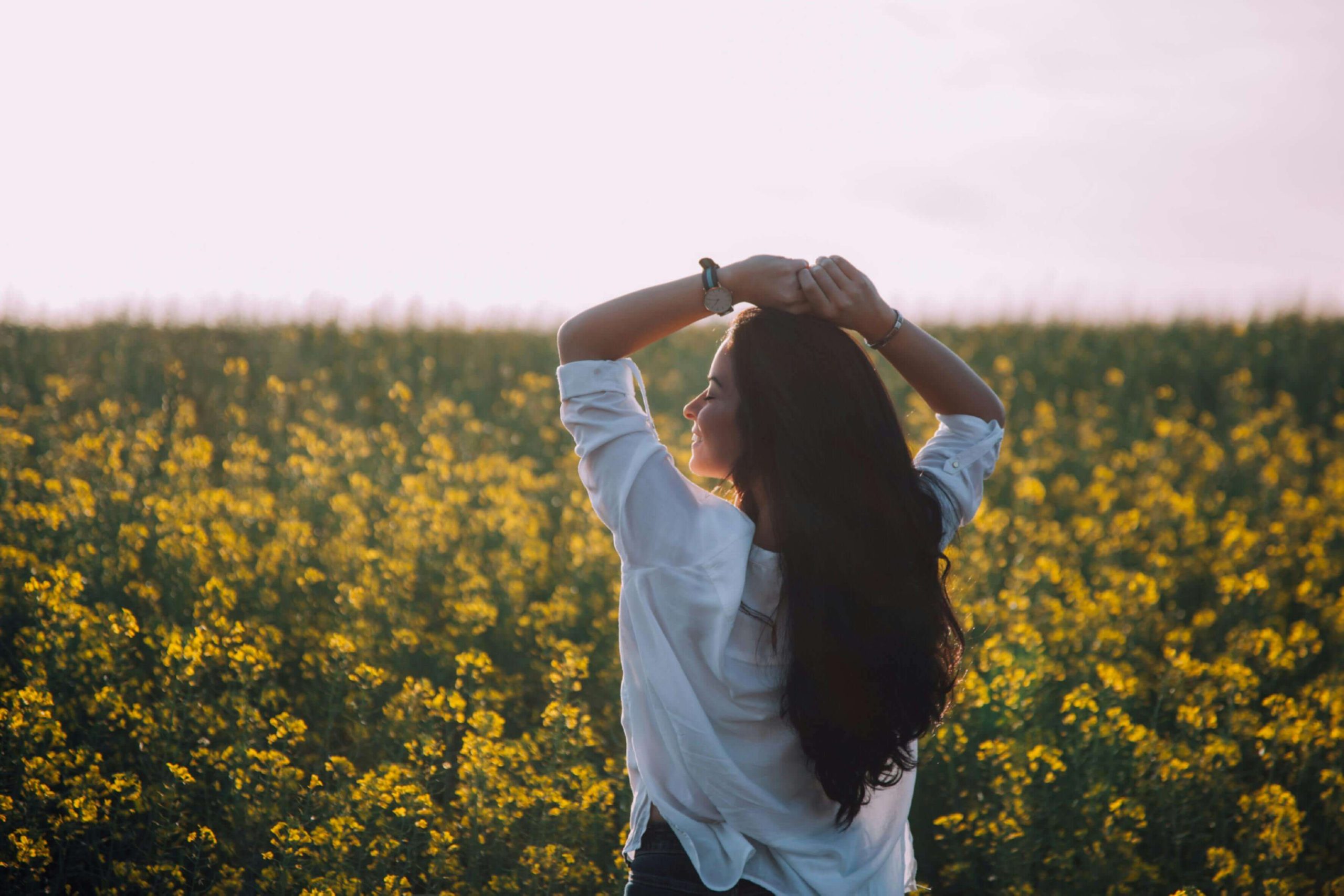 Person standing in a yellow flower field at sunrise, stretching and breathing deeply, symbolizing clarity and rejuvenation that can accompany IV hydration therapy in Tempe, AZ.