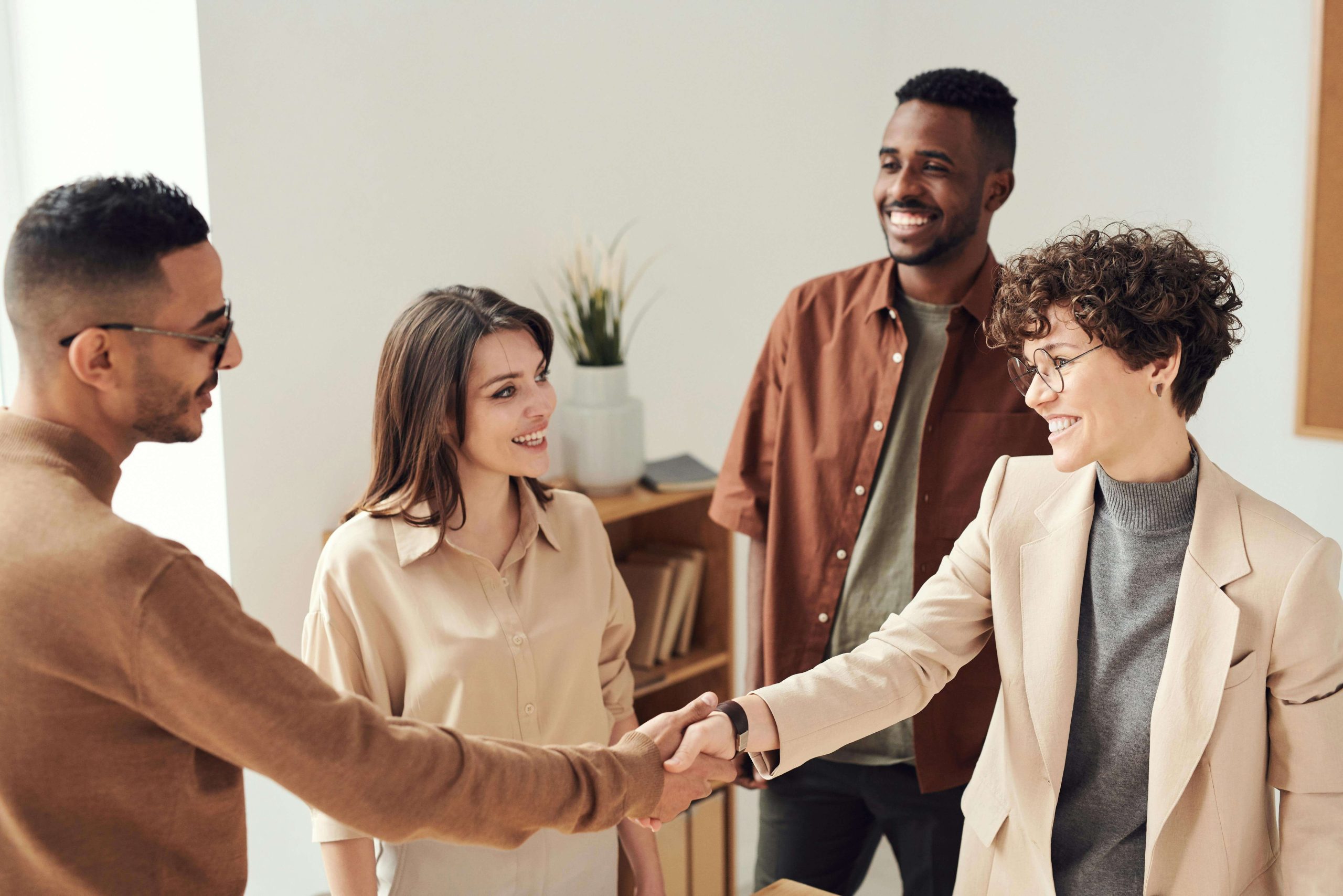 Colleagues smiling and shaking hands in a bright office, showing how connection and balance are key goals in psychiatry in Tempe, AZ.