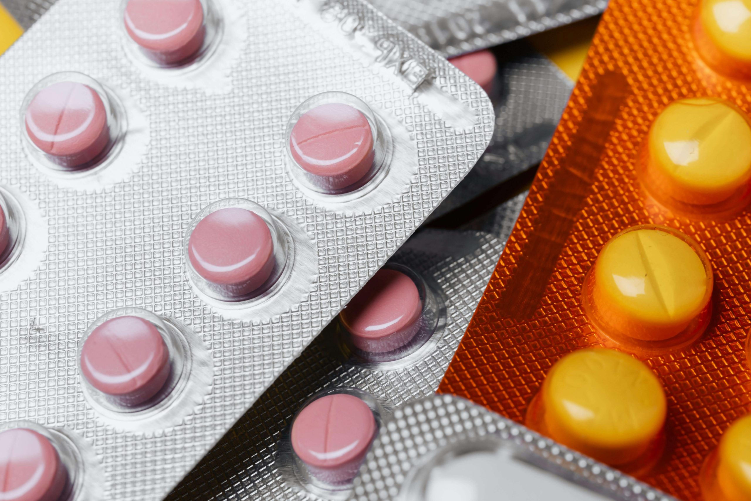 Close-up of colorful blister packs with yellow and pink tablets, representing psychiatric medication prescribed by a psychiatrist in Tempe, AZ to treat anxiety and depression.