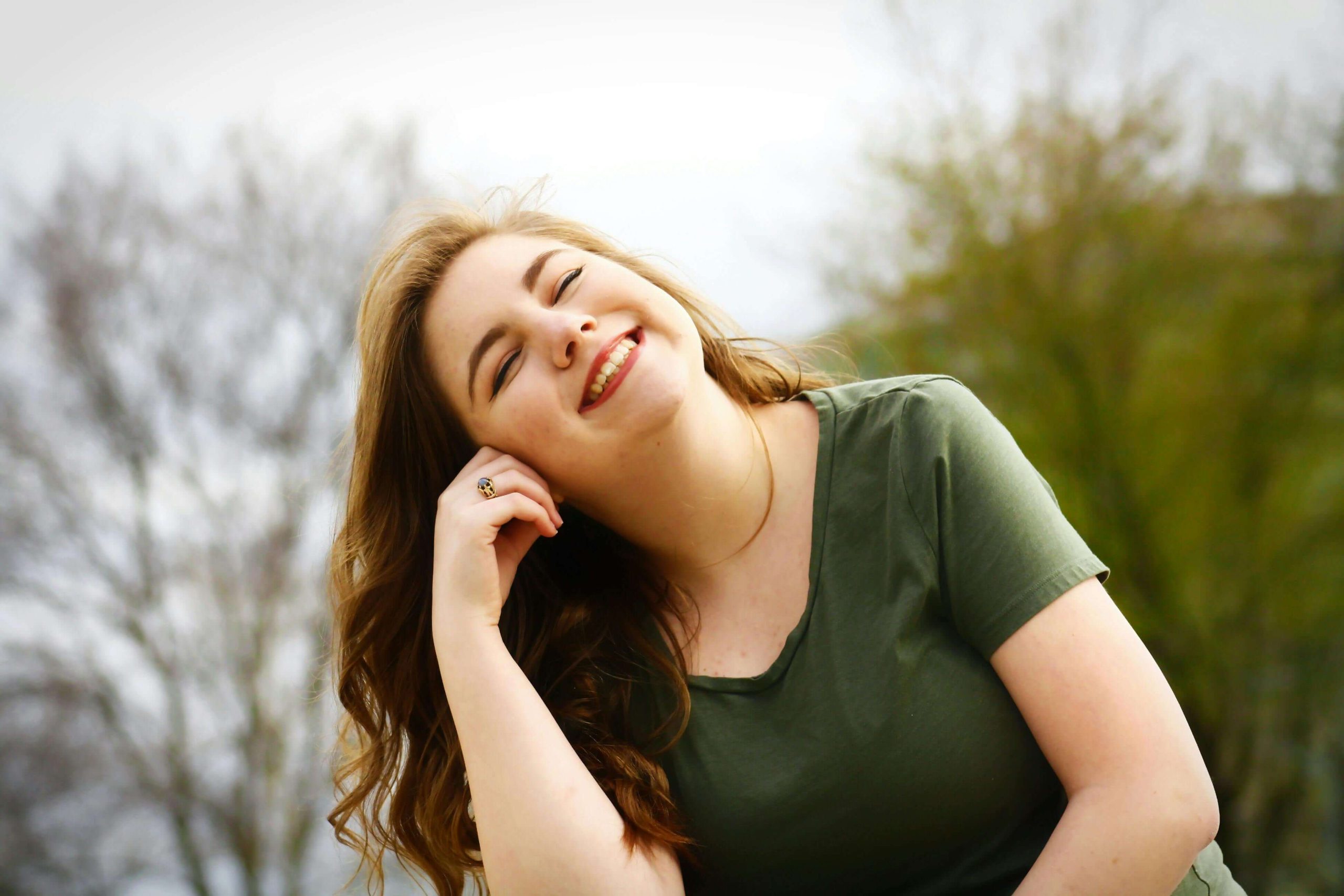 A young woman smiles warmly while enjoying time outdoors, reflecting the improved mood stability that can come from medication management in Tempe, AZ.