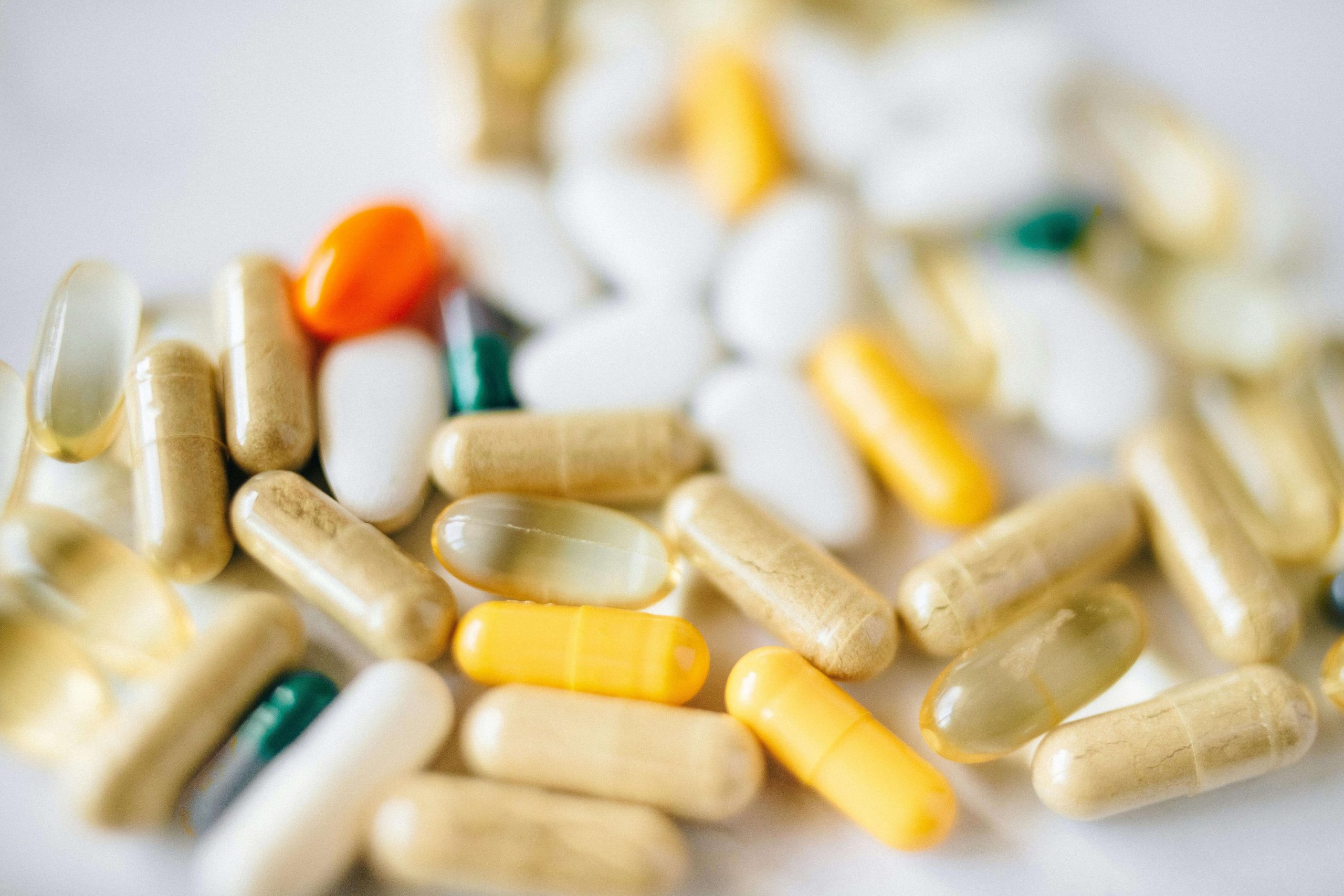 A variety of colorful capsules and tablets are scattered on a white surface, representing the different prescriptions often used in medication management in Tempe, AZ.
