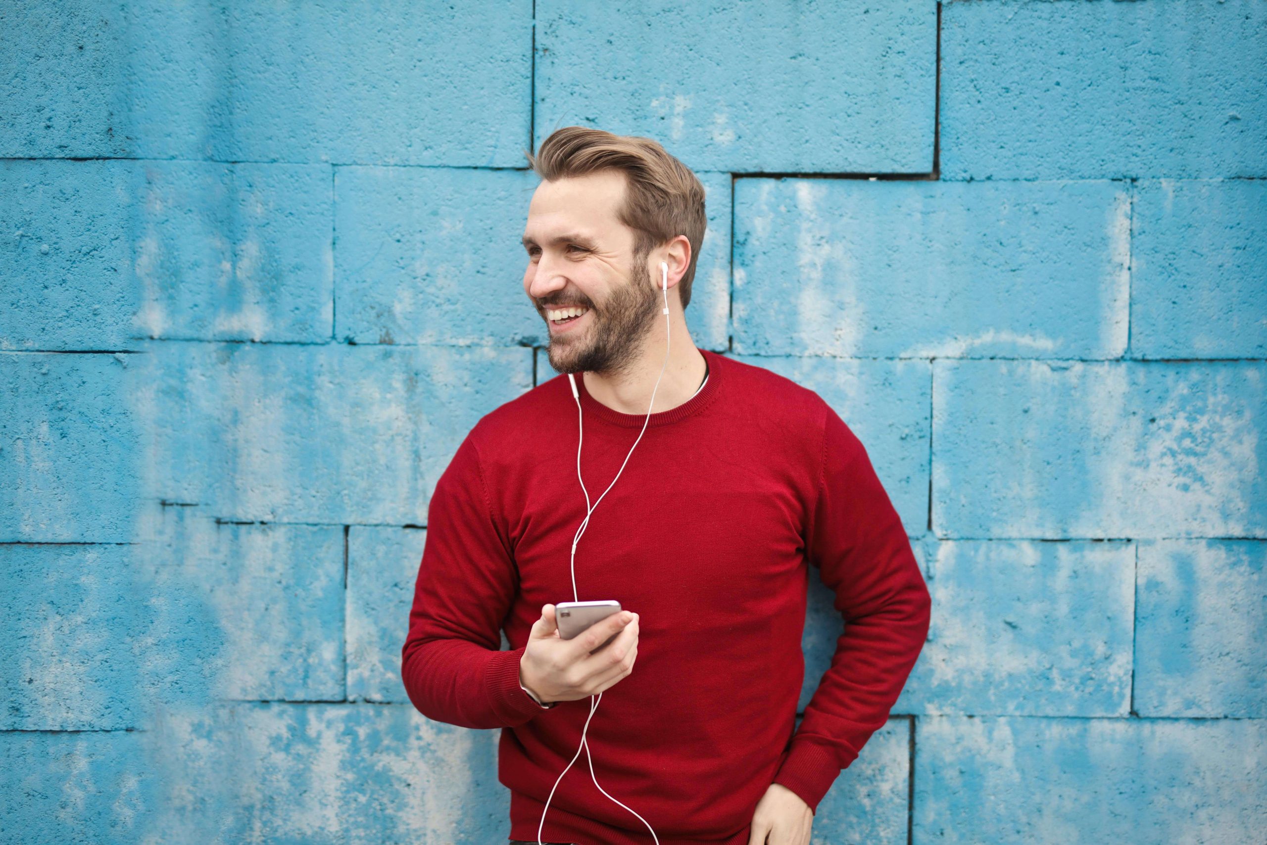 Man in Red Sweater - tempe psychiatry - psychiatric care tempe - psychiatrist tempe az - phx - phoenix - gilbert - scottsdale - mesa - arizona Man in a red sweater smiling while listening to music, representing the balance and relief that can come from working with a psychiatric professional in Tempe, AZ.