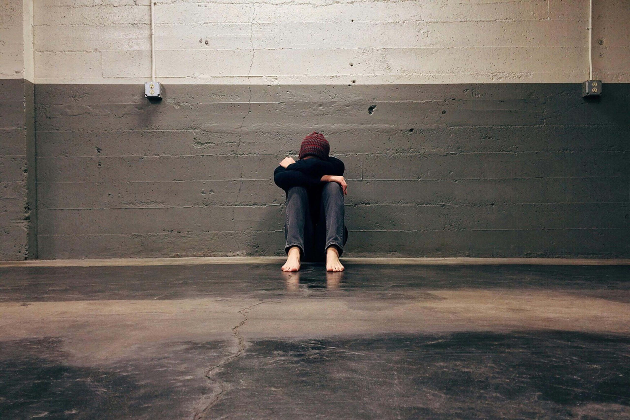 Person sitting alone on the floor with head down, symbolizing the emotional toll of untreated anxiety and depression, highlighting the need for psychiatric care in Tempe.