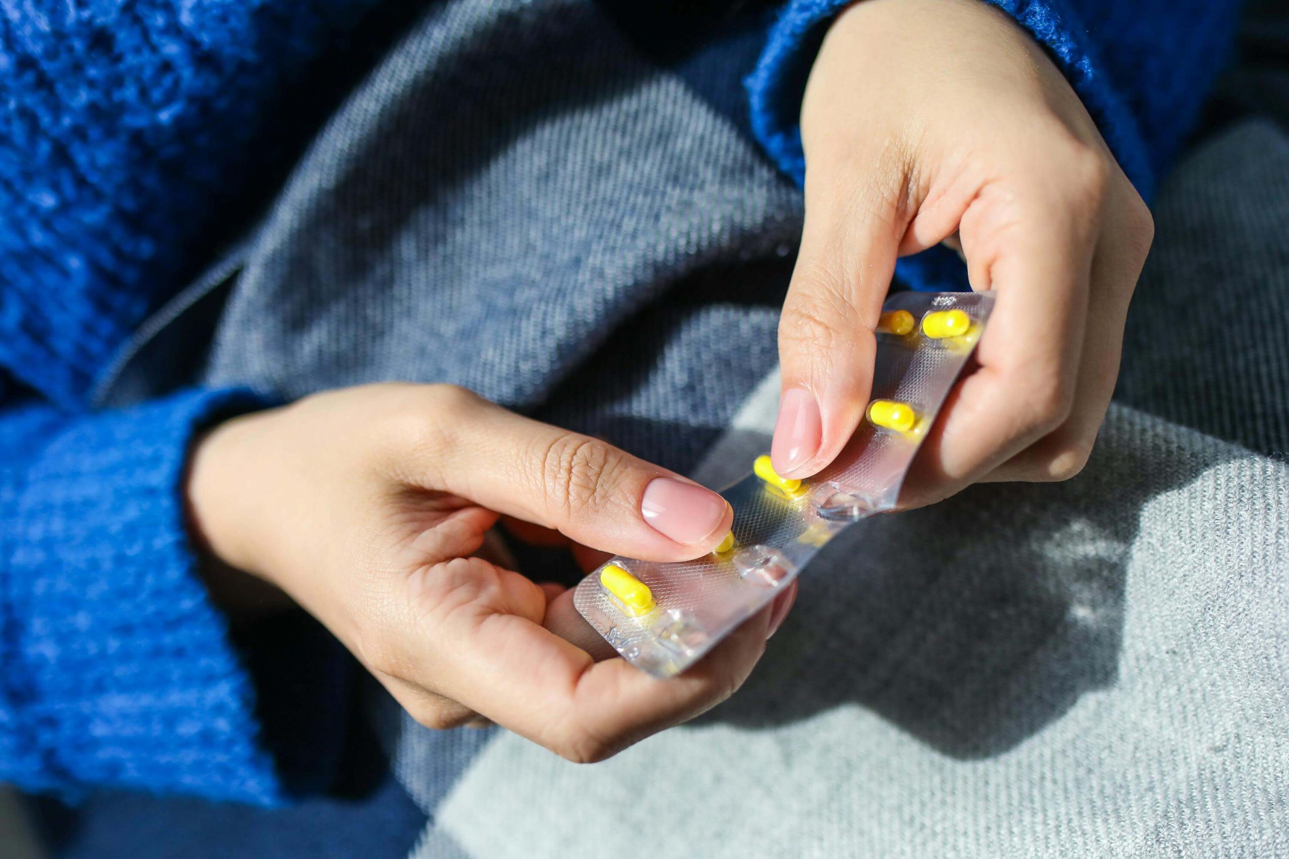 Person handling prescribed yellow capsules, illustrating medication management in mental health treatment in Tempe, AZ.