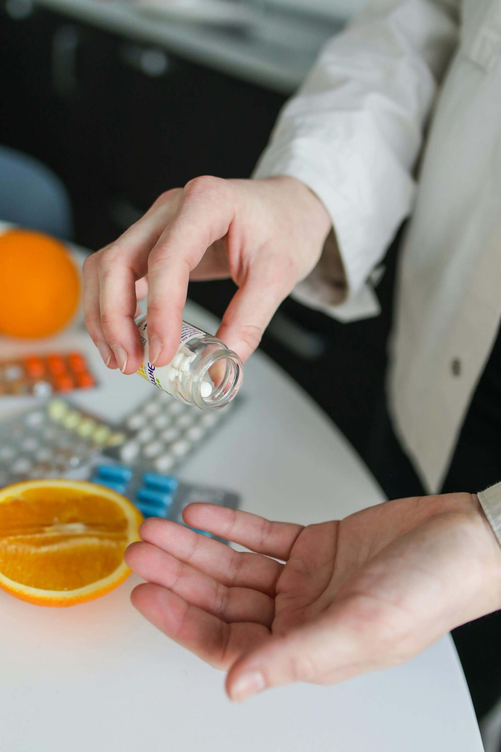 Hands dispensing pills from a prescription bottle over a table, illustrating support from psychiatry in Tempe, AZ, for medication management.