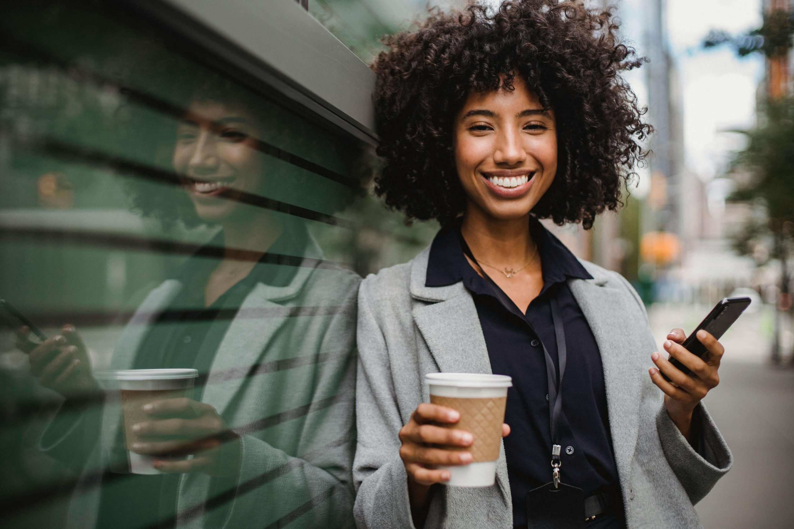 Confident Woman Smiling - iop for substance use tempe, az - substance abuse treatment tempe, az - intensive outpatient programs - phx - phoenix - gilbert - scottsdale - mesa - arizona - chandler Confident woman smiling outdoors while holding a coffee and phone, representing empowerment, balance, and growth supported by IOP for substance use in Tempe, AZ.