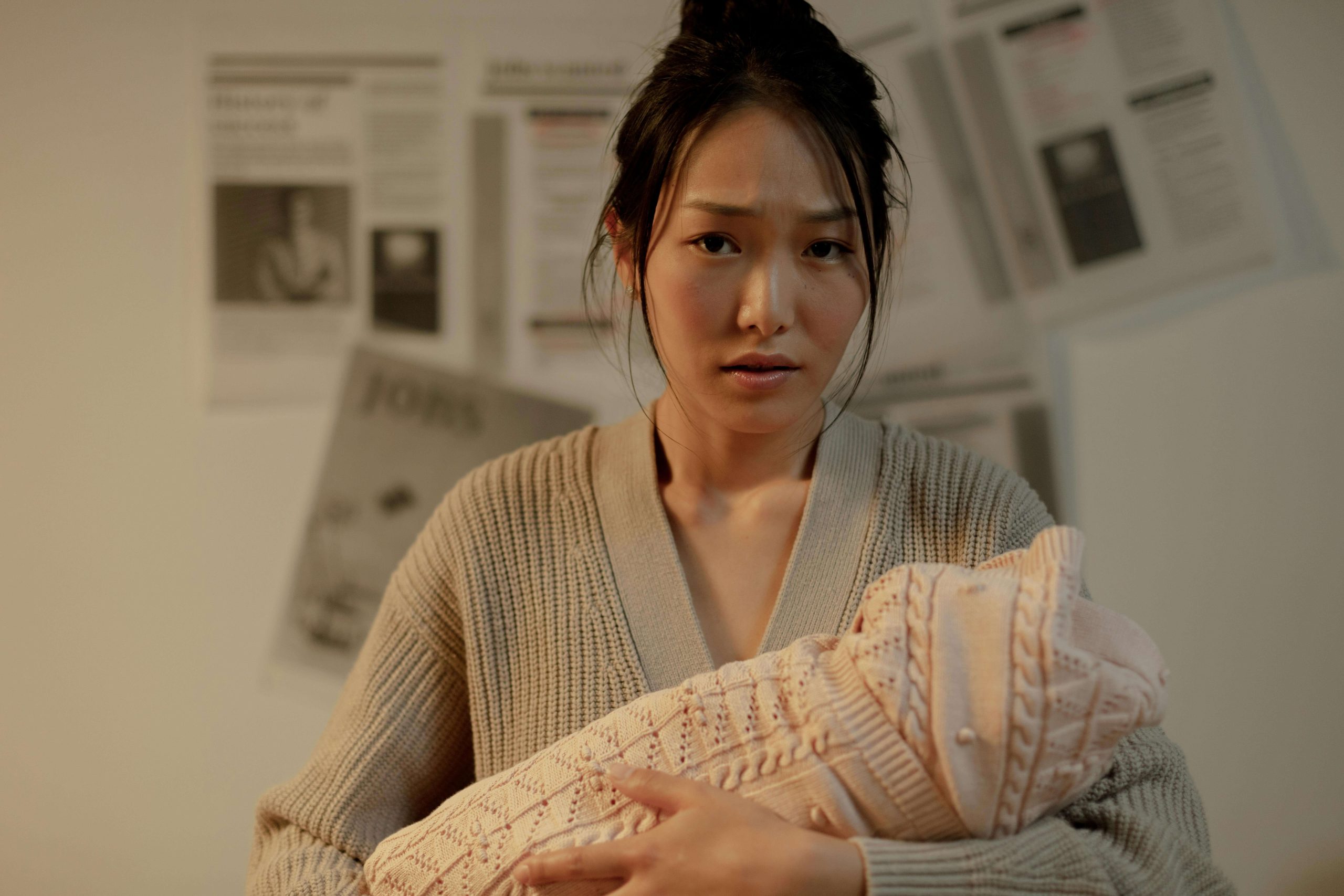 New mother holding her baby while looking overwhelmed, illustrating the emotional strain of postpartum depression and the importance of psychiatry in Tempe, AZ for support.