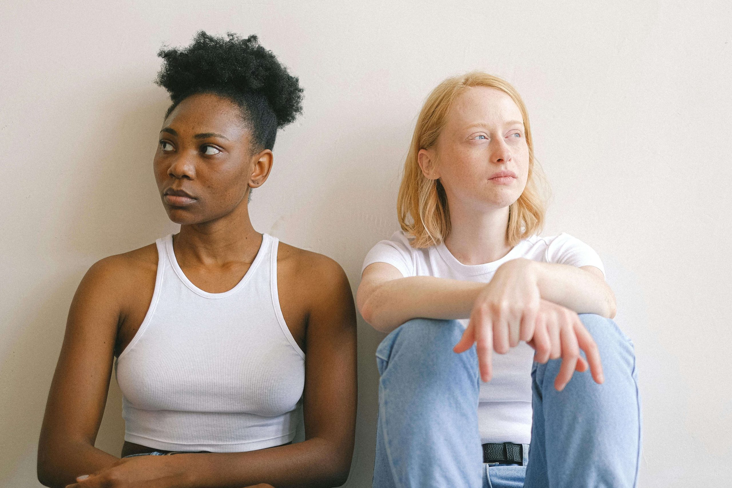 Two people sitting quietly against a wall, illustrating dissociation and numbness that ketamine therapy in Tempe, AZ can help treat.